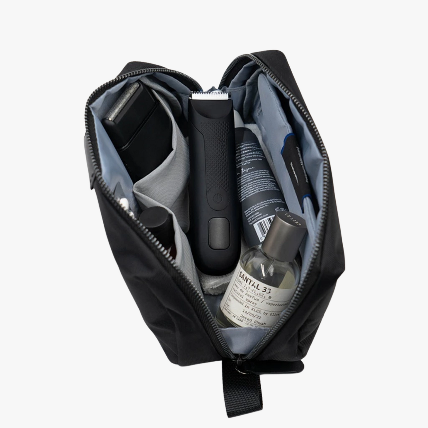 Black toiletry bag with grooming products including a bottle and a razor.