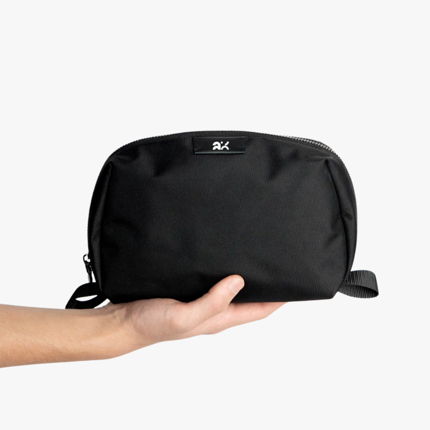 Black pouch held in a hand on a white background