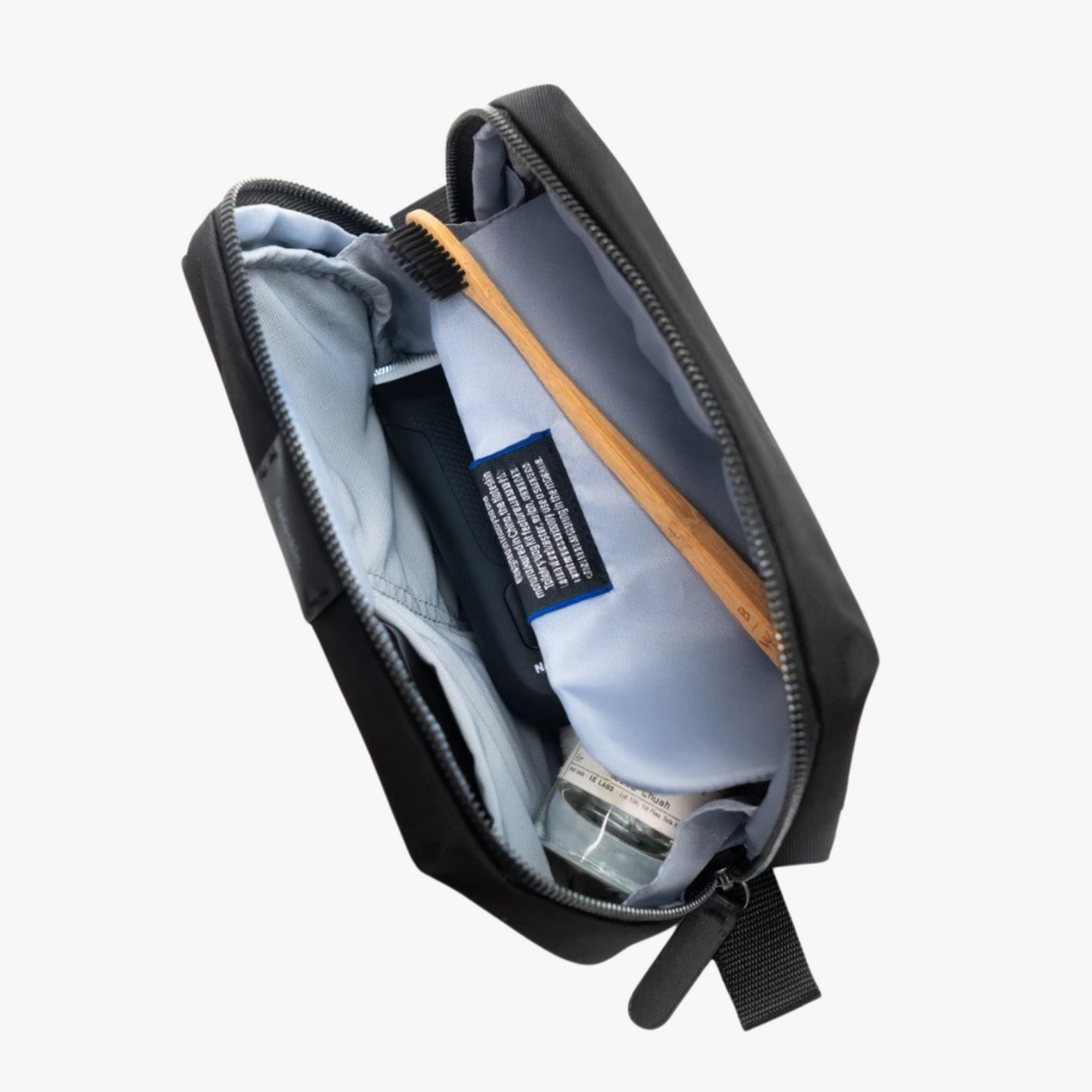 Black toiletry bag with a bottle and brush inside on a white background