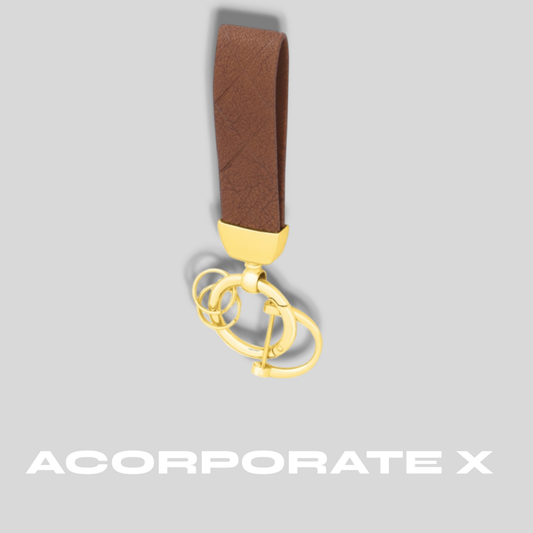 Gold keychain with brown strap on a gray background, featuring the brand 'ACorporate X'.